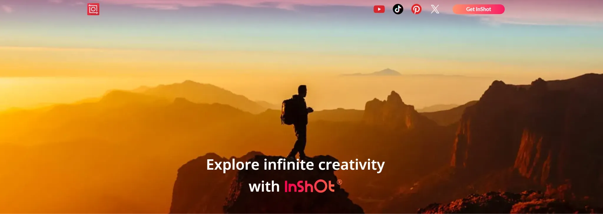 A hiker stands on a mountain peak during a vibrant sunset.