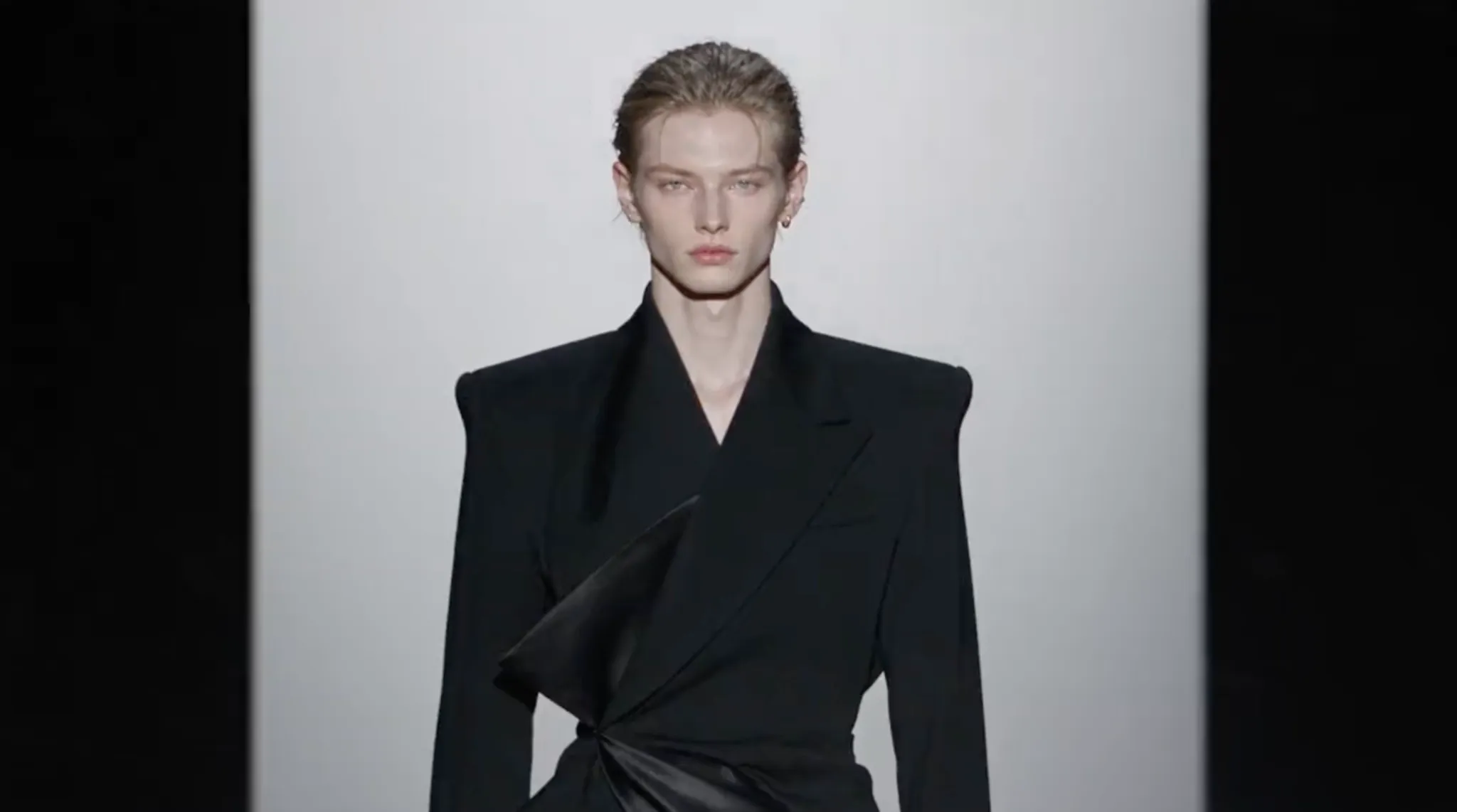 A model poses in a stylish black blazer with unique draping details.