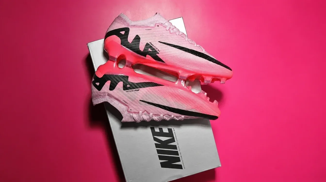 A pair of pink Nike soccer cleats on a white box against a pink background.