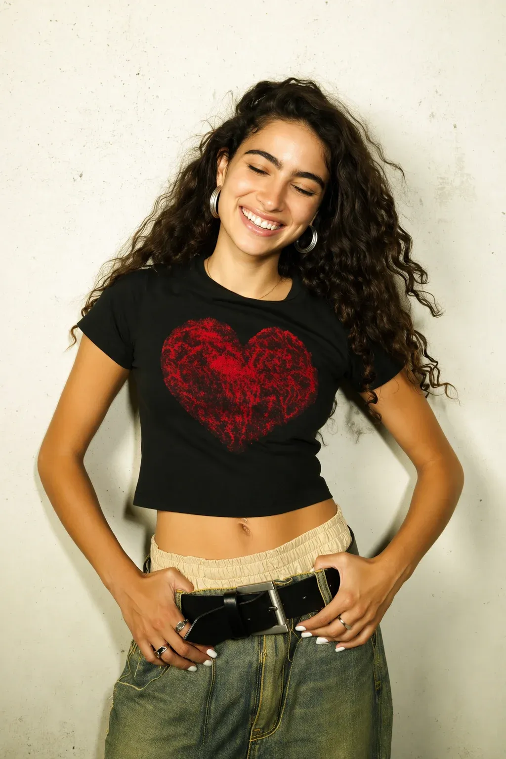A woman smiles while wearing a black crop top with a red heart design.