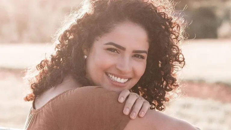 Portrait rapproché d'une femme souriante aux cheveux bouclés au soleil
