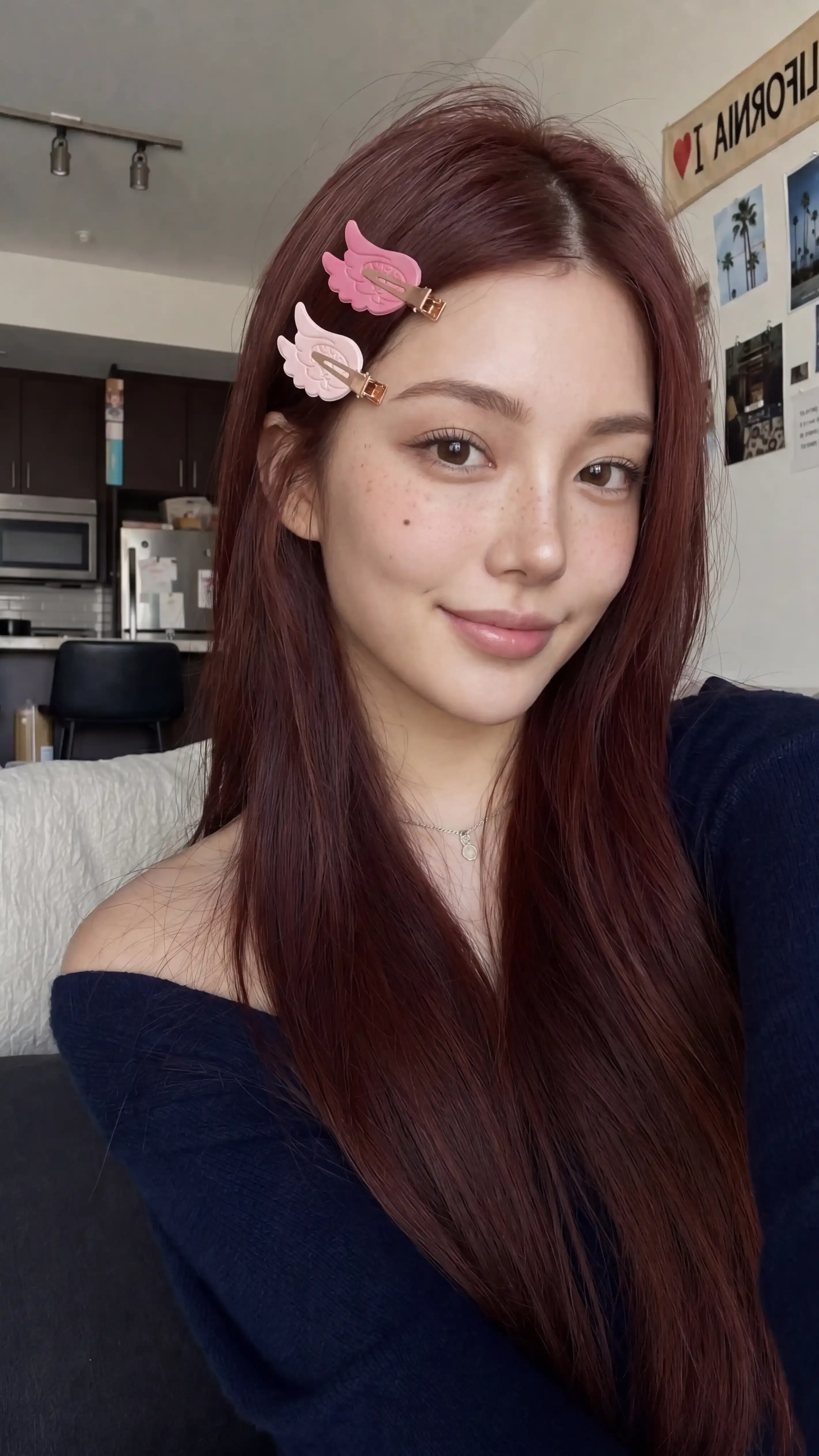 A young woman smiles with pink hair clips in her long, reddish-brown hair.
