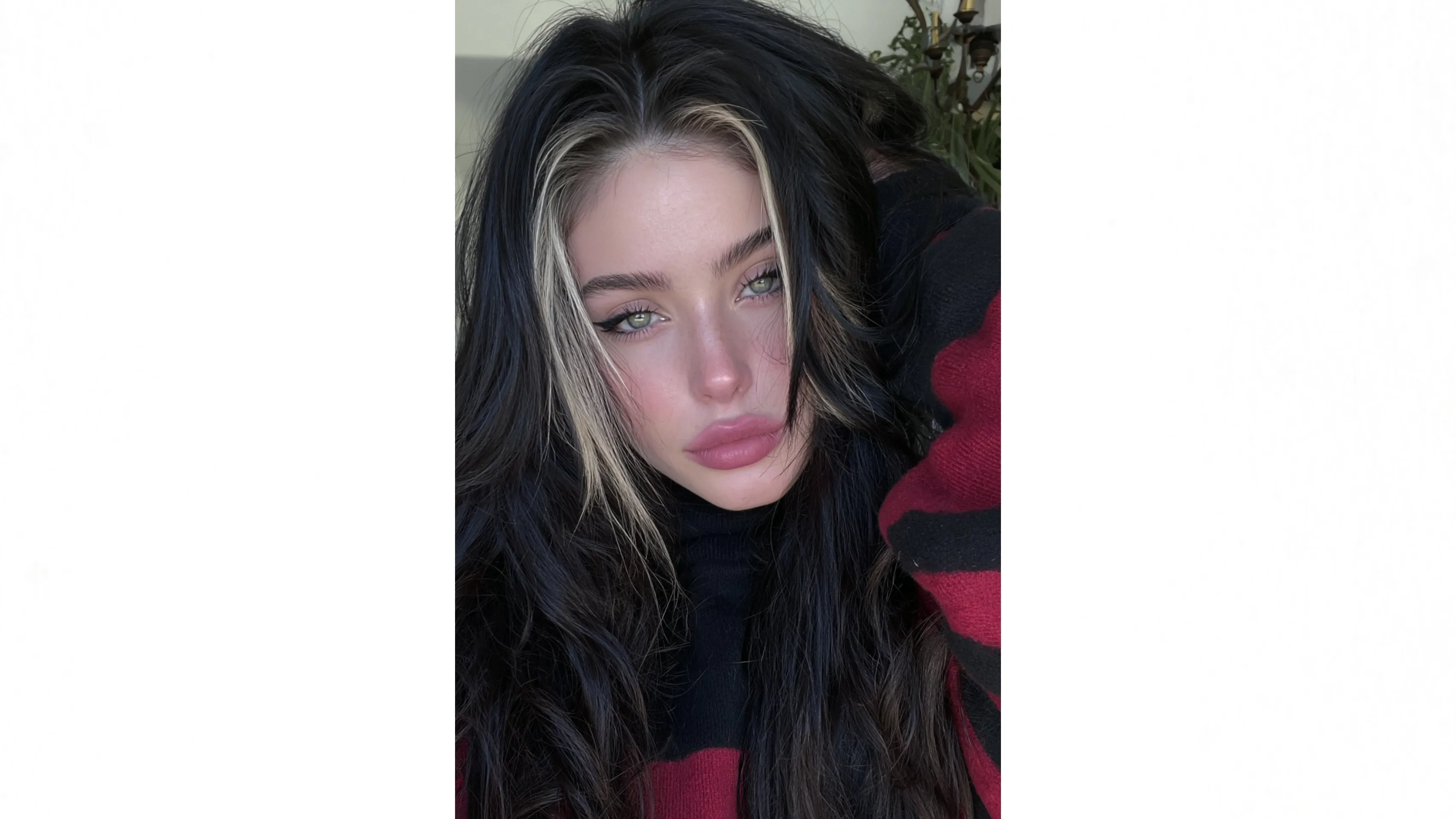 A young woman with long black hair and highlights poses for a close-up selfie.
